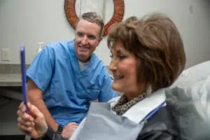 our dentist in Garland, Dr. Scott Dooley, with a happy elderly patient after getting her new dental implants
