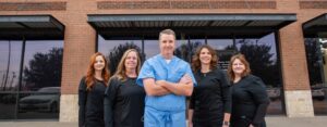 Dr. Scott Dooley & Team Smiling in front of Garland, TX dental practice