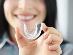 A patient holding up a mouthguard used for sleep apnea treatment in Garland, TX